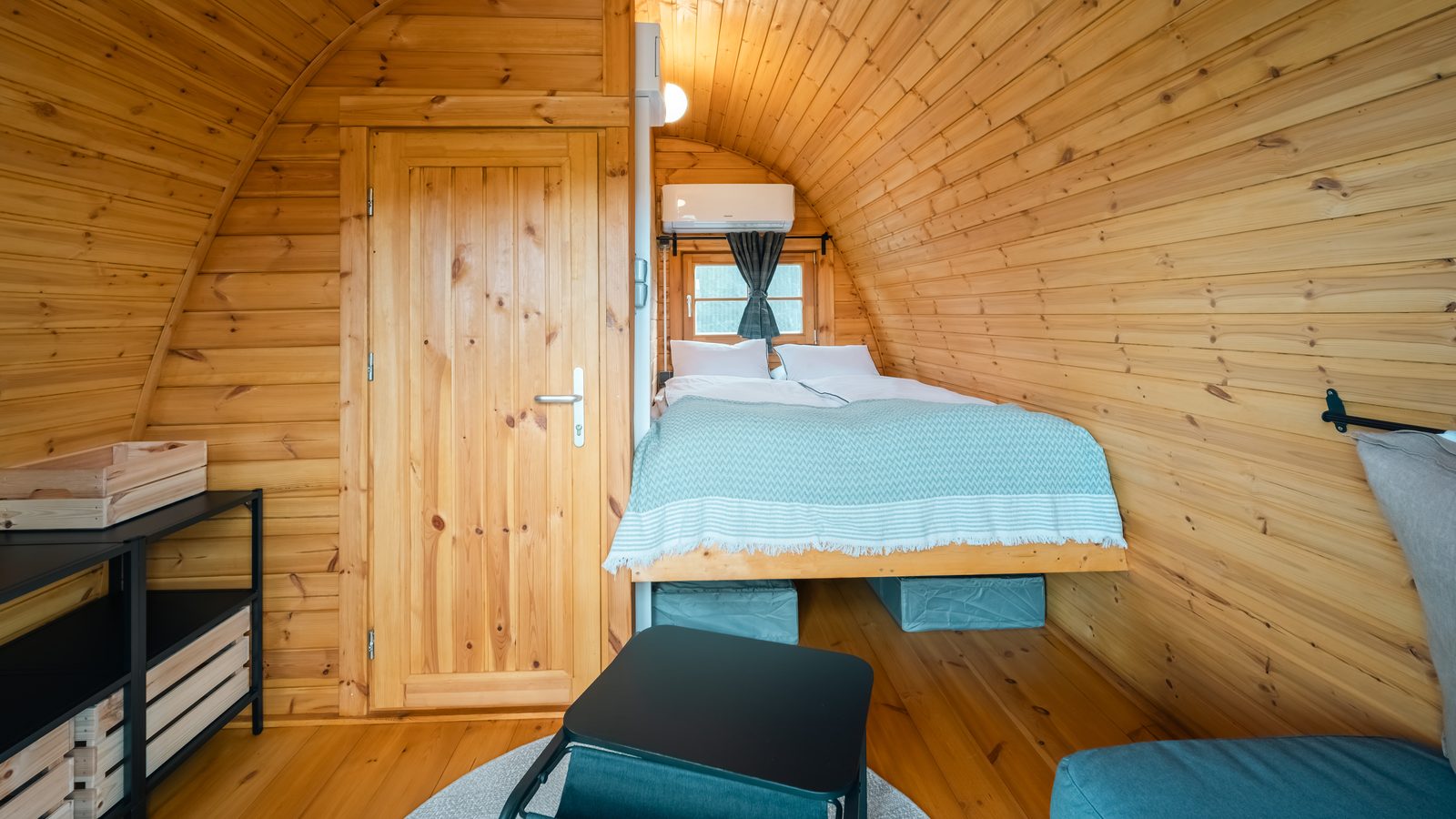 Unutrašnjost glamping kućice: bračni krevet i klima uređaj